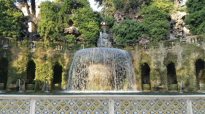 A beautiful garden scene with a fountain at its center, encircled by flourishing trees and diverse plant life.